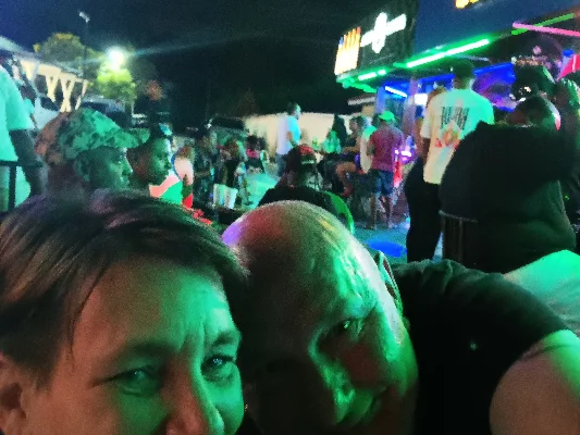 Manuela y Rainer tomándose una selfie en un evento nocturno con luces coloridas.