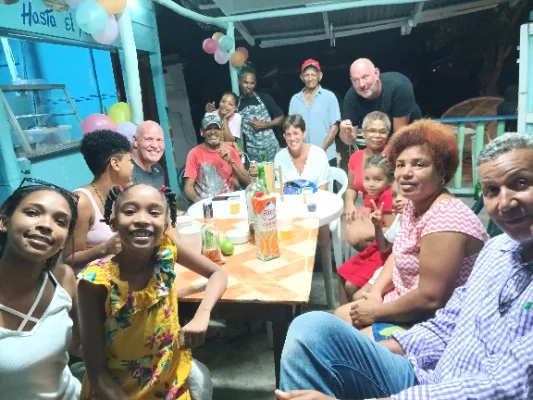 Grupo de personas celebrando al aire libre con globos y bebidas.